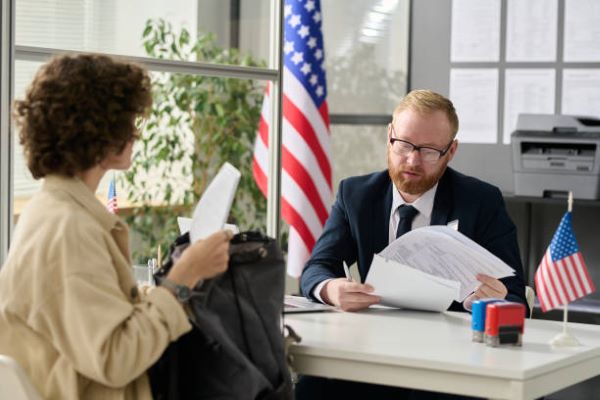 visa L1.un hombre sentado en un escritorio con una mujer, revisando unos papeles